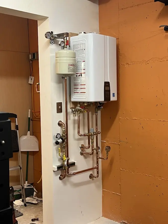 Plumbing technician inspecting water heater connections in Hays